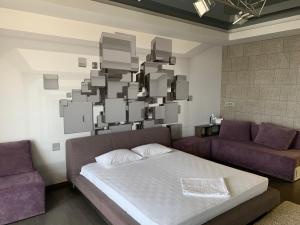 キーウにあるApartments Raisy Okipnoiのベッド1台、ソファ、絵画が備わる客室です。