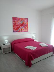 una camera da letto bianca con un letto con una coperta rossa di Al Saliceto Hotel a Patti
