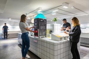 zwei Frauen stehen an einer Theke und bereiten Essen in einem Restaurant vor in der Unterkunft a&o Düsseldorf Hauptbahnhof in Düsseldorf