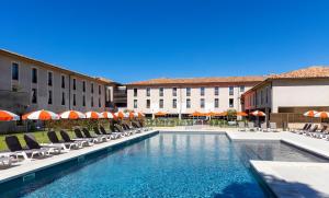 une piscine avec des chaises et des parasols dans un hôtel dans l'établissement Grand Prix Hôtel & Restaurant, au Castellet