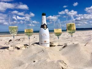 a bottle of champagne and four wine glasses on the beach at "Steuermannskammer" by Ferienhaus Strandgut in Born