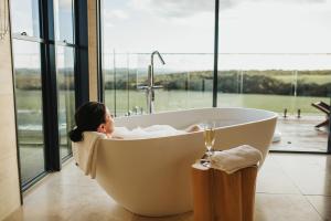 una mujer tumbada en una bañera en una habitación con ventana en StowAway Kangaroo Island en Stokes Bay