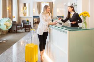 HiLight Suites Hotel في فيينا: سيدتان واقفتان على منضدة مع حقيبة صفراء