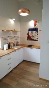 una cucina con mobili bianchi e un lavandino di Apartament Ogarna 37 a Danzica