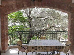 a table and chairs on a balcony with a tree at Zoro Apartments in Sveti Stefan