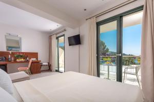 a hotel room with a bed and a balcony at Tosca Beach Hotel in Paleo Tsifliki