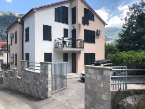a large white house with black shuttered windows at APARTMANI PETRIJA in Prčanj