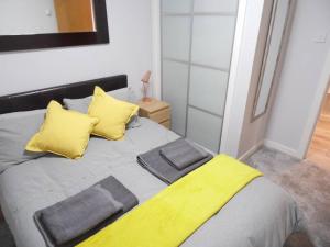 um quarto com uma cama com almofadas amarelas em Art Deco Building on Vibrant Sauchiehall Street em Glasgow