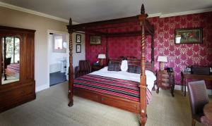 1 dormitorio con cama con dosel y papel pintado de color rosa en The Museum Inn en Farnham