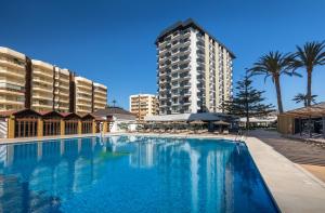 a large swimming pool in front of a tall building at Occidental Fuengirola in Fuengirola