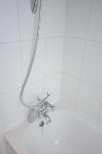um chuveiro numa casa de banho em azulejos brancos em Four Bedroom Townhouse 12 Minutes Walk to Excel Exhibition Centre em Londres