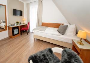 a bedroom with a bed and a desk with a chair at Gästehaus & Apartments fliegendes Perlhuhn Borgfeld in Lilienthal