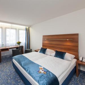 ein Hotelzimmer mit einem großen Bett und einem Schreibtisch in der Unterkunft Hotel Strohgäu in Korntal-Münchingen