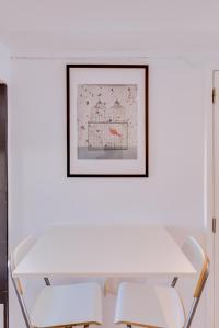 Biały stół z dwoma krzesłami i zdjęciem na ścianie w obiekcie À da Avó -The Guesthouse w Faro