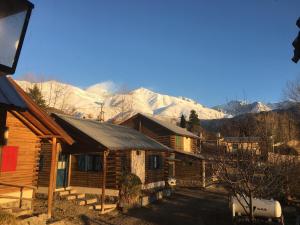 Cabaña de madera con montañas cubiertas de nieve en el fondo en Cabañas del Mesón, en Potrerillos
