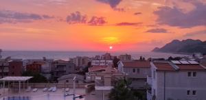einen Sonnenuntergang über einer Stadt mit Gebäuden und dem Meer in der Unterkunft Apartments Diva in Dobra Voda