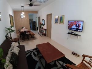 a living room with a couch and a tv on a wall at ORCHIDD HOMESTAY in Gambang