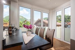 a dining room with a table and chairs and windows at Appartements Schwaighofer in Kössen