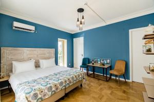 a bedroom with blue walls and a bed and a desk at Gvino Minda in Tbilisi City