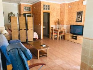 uma sala de estar com um sofá, uma televisão e uma mesa em Hostal la Tarayuela em Barbate