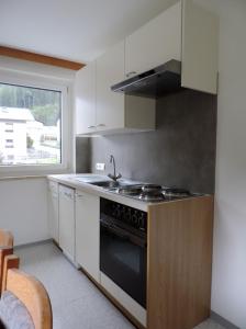 a kitchen with a stove and a sink and a window at Apartments Alpenrose in Flirsch