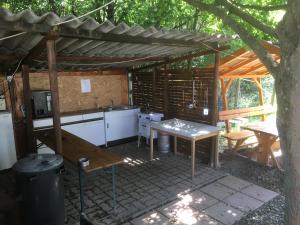 una cocina bajo una pérgola de madera con una mesa en Börzsönyi Szabadidőközpont, en Kóspallag