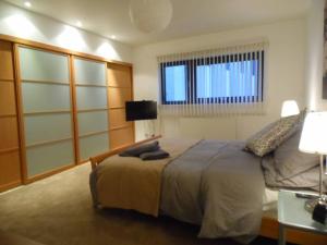 a bedroom with a bed and a table and a window at Modern 2-bedroom Apt near SSE Hydro and SEC in Glasgow