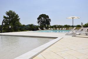 a swimming pool with chairs and an umbrella at Seiterre Agriturismo Tenuta San Leone in Valeggio sul Mincio