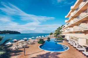 un resort con piscina, sedie e oceano di Iberostar Selection Jardín del Sol Suites - Adults Only a Santa Ponsa