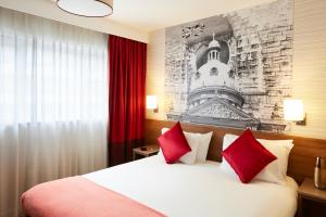 バーミンガムにあるアパートホテル アダージョ バーミンガム シティセンターの赤い枕のベッドが備わるホテルルームです。