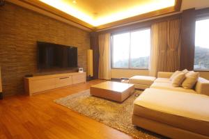 a living room with a couch and a flat screen tv at Hotel Gendairakuen Isehara in Isehara