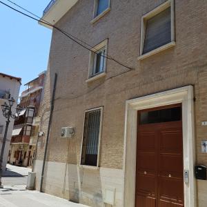 un bâtiment en briques avec une porte rouge dans une rue dans l'établissement Eden Room, à Margherita di Savoia