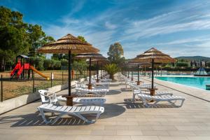 a row of chairs and umbrellas next to a pool at Il Veliero in Follonica