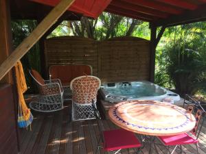 bañera de hidromasaje en una terraza con sillas y mesa en Middle Country 97-1 "la recette du bonheur" en Deshaies
