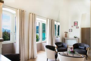 a living room with chairs and a table and windows at Impérial Palace in Annecy