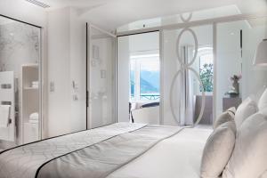 a white bedroom with a bed with a large mirror at Impérial Palace in Annecy