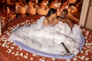 un homme et une femme assis dans une baignoire remplie de mousse dans l'établissement Paradise Stream Resort, à Mount Pocono