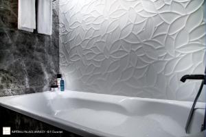 a white bath tub in a bathroom with a wall at Impérial Palace in Annecy