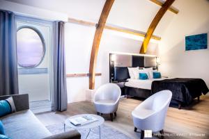 a hotel room with a bed and two white chairs at Impérial Palace in Annecy