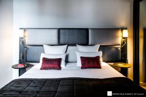 a bedroom with a large bed with two red pillows at Impérial Palace in Annecy