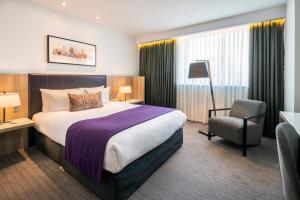 a hotel room with a bed and a chair at Park Regis Birmingham in Birmingham