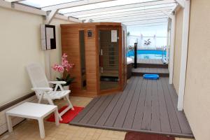 a deck with a hot tub and chairs and a pool at Villa Happy Rose in Dąbki