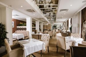 a restaurant with white tables and chairs and white tables and chairs at Hotel Alkor in Truskavets