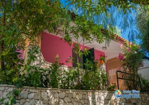 uma casa rosa e branca com uma parede de pedra em Camping Village degli Ulivi em Mattinata