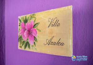 a sign with a pink flower on a purple wall at Camping Village degli Ulivi in Mattinata