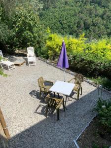 einen Tisch, Stühle und einen Regenschirm auf einer Kiesterrasse in der Unterkunft La porta del Sole in Seborga