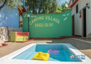 een zwembad voor een gebouw met een bord bij Camping Village degli Ulivi in Mattinata