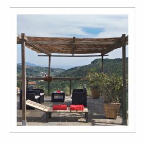 a wooden gazebo with couches and a table at Agriturismo OlivArancio in Leivi