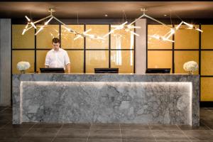 un homme debout derrière un comptoir dans un hall dans l'établissement William Gray by Gray Collection, à Montréal