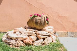 una maceta de flores sentada sobre un montón de rocas en Theodora Corfu Holiday Apartments, en Ýpsos
